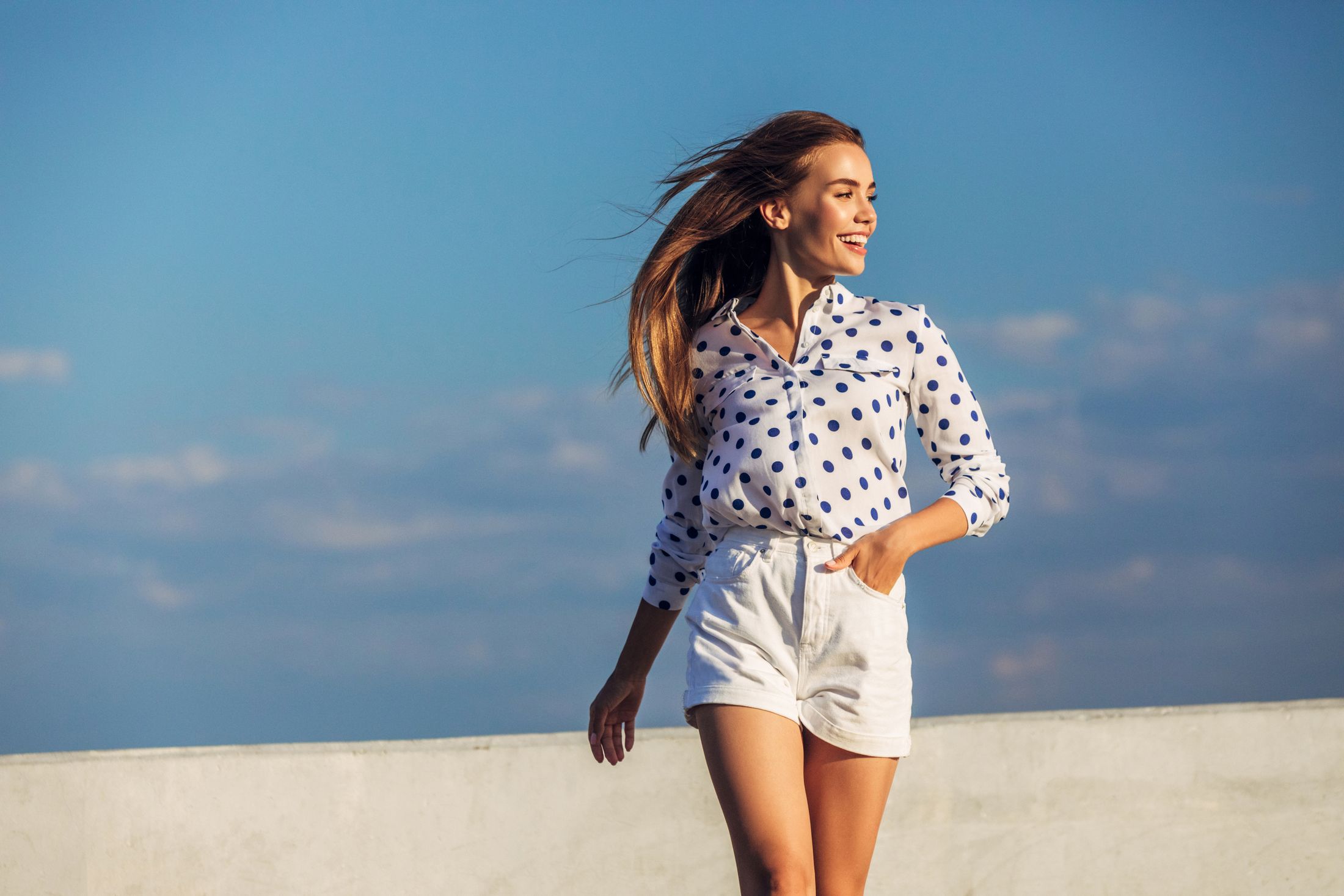 Smiling woman walking in polka dot shirt.