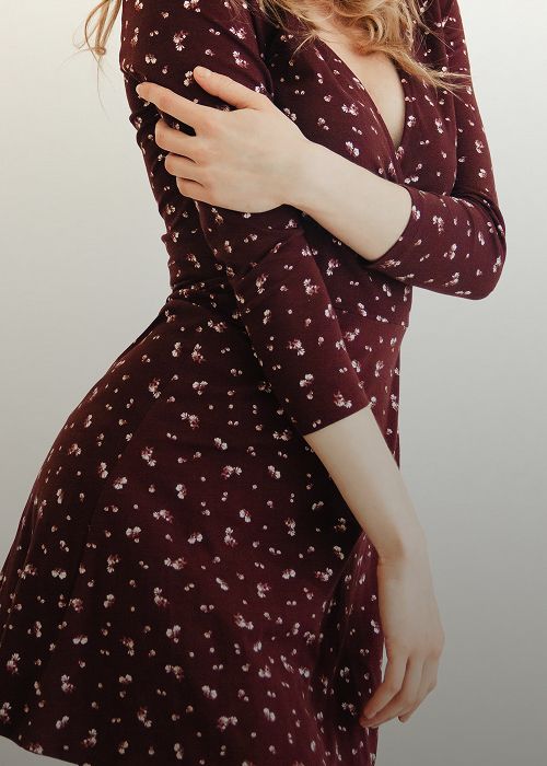 Woman in floral dress with crossed arms.